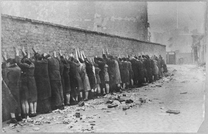 Des Juifs capturés sont alignés contre le mur du ghetto